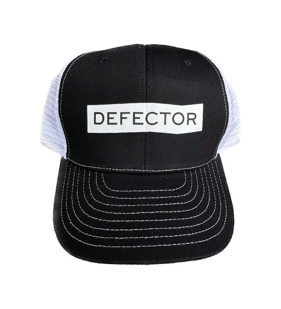 Defector black trucker hat with white Defector logo printed in the center of the front. Back mesh is white.