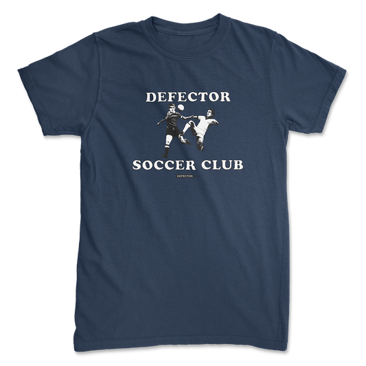 Defector shirt that says “DEFECTOR SOCCER CLUB.” Features clip art of soccer players.  Blue shirt in ‘unisex’ cut.